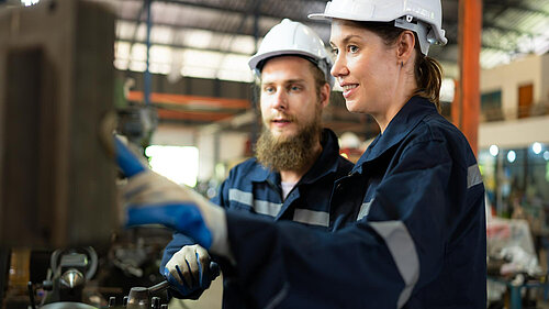 Two people using a machine.